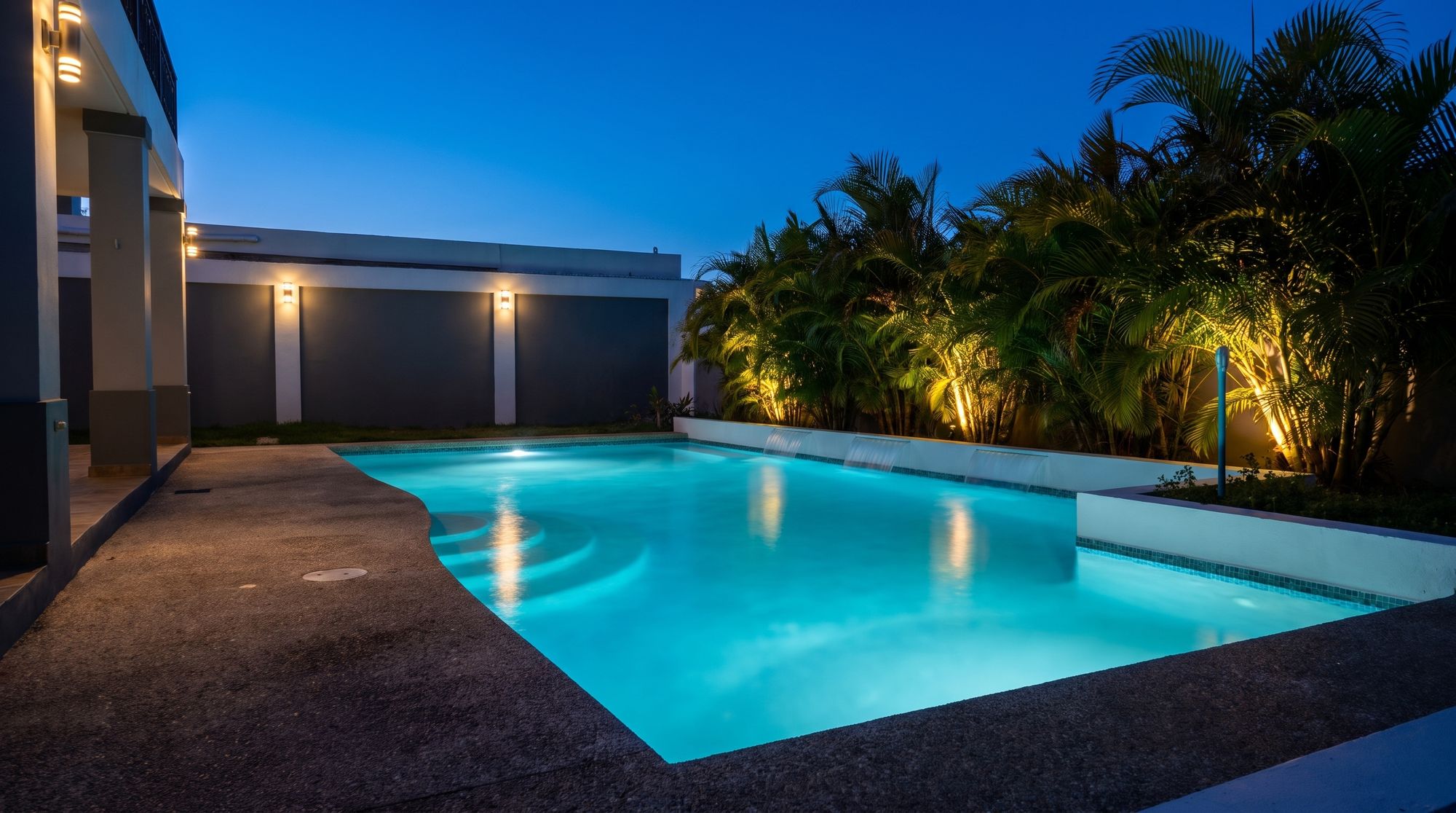 Piscina iluminada de noche entre palmas