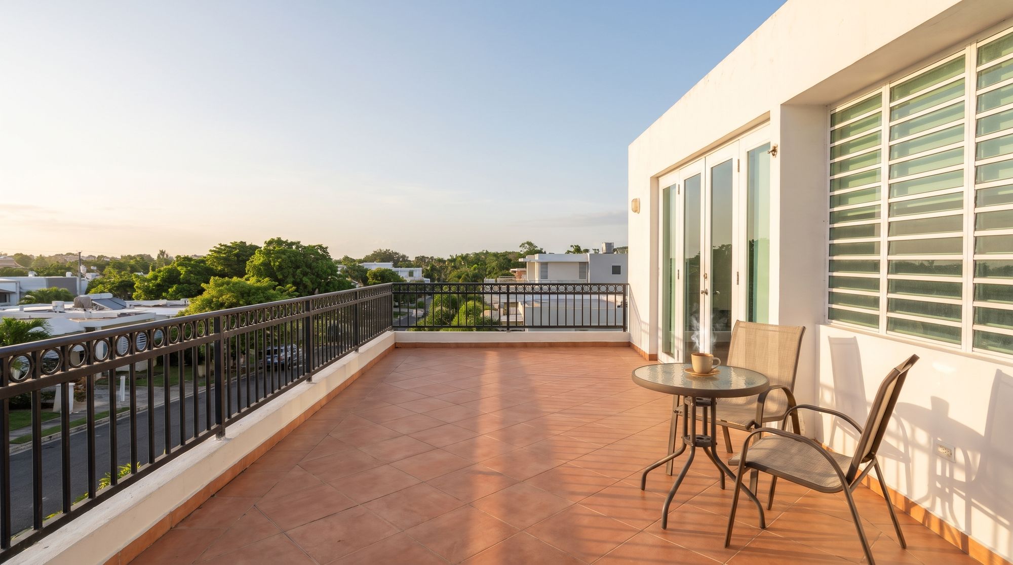 Terraza al amanecer con piso terracota, baranda y mesa para el café